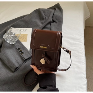 Gros plan d'un mini sac à bandoulière en cuir marron avec pendentif doré et lettrage