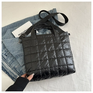 Gros plan du sac cabas matelassé noir avec texture doudoune et doubles anses sur denim