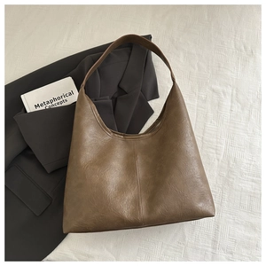 Détail d'un sac cabas en cuir vintage marron avec texture grainée et couture verticale