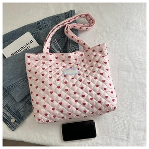 Detail of pink quilted tote bag with red heart pattern and soft padded texture