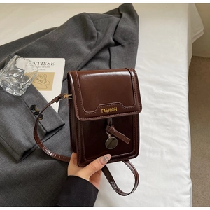 Gros plan d'un sac bandoulière en cuir marron foncé brillant avec texte doré Fashion
