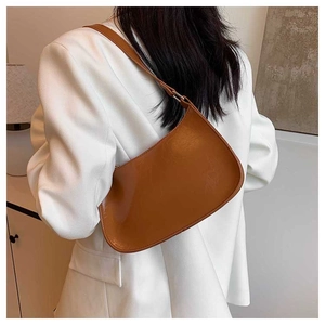 Brown hobo underarm bag shown on model wearing white blazer for style and scale
