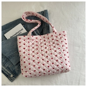Detailed view of pink quilted tote bag with red heart pattern and dual handles