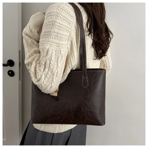 Détail d'un sac cabas marron foncé avec texture plissée vintage et surpiqûres blanches