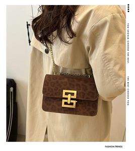 Detail of leopard print flap bag with gold rectangular lock and chain strap on trench coat