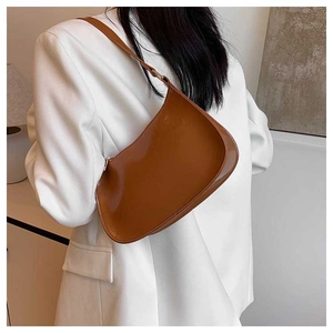 Brown faux leather crescent underarm bag styled on a white blazer for a chic look