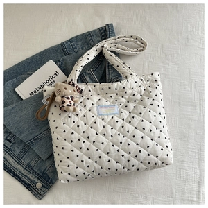 Detailed shot of white quilted tote with black heart embroidery and cute cat charm