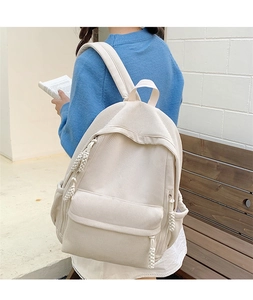 Detail eines beigefarbenen Cord-Rucksacks mit strukturiertem Stoff und Seitentaschen am Modell