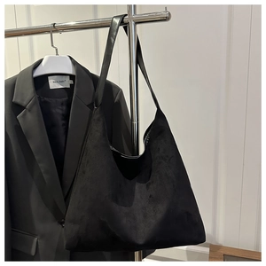 Detail of black matte suede hobo bag with slouchy crescent shape and leather strap
