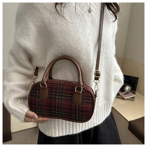 Close-up of vintage red and green plaid shell bag with leather handle and gold hardware