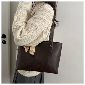 Détail d'un cabas marron foncé à texture vintage avec foulard en soie jaune élégant
