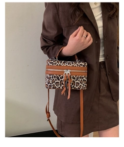 Détail du sac seau à imprimé léopard avec bordure en cuir marron et zip métallique
