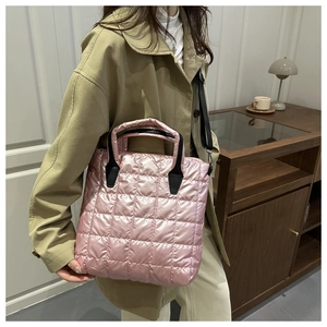 Close-up of pink quilted puffer bucket bag with contrast black handles and strap