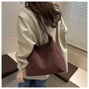 Brown suede hobo tote bag with a minimalist wide shoulder strap shown on model's shoulder