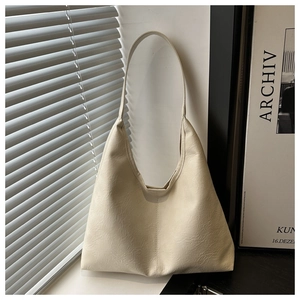 Gros plan du sac cabas blanc crème à texture douce sous une lumière naturelle tamisée