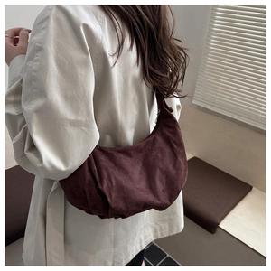 Détail d'un sac à bandoulière en velours côtelé marron plissé porté par un mannequin