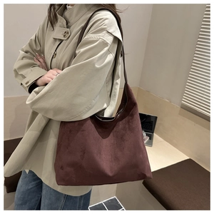 Detail of burgundy tote bag showing soft matte texture and leather straps on shoulder