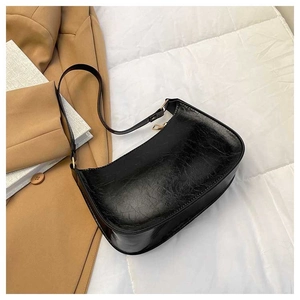 Detail of black glossy crinkled patent leather texture and gold zipper on underarm bag