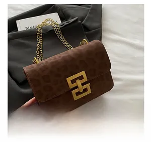 Detail of leopard print suede crossbody bag featuring gold chain and geometric clasp