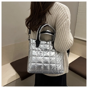 Sac fourre-tout argenté matelassé avec poignées noires porté par un mannequin
