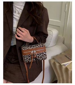 Détail du sac boîte imprimé léopard avec bordure en cuir marron et fermetures à glands
