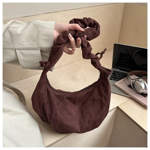 Sac croissant en velours côtelé marron avec anse plissée nouée sur un bureau élégant