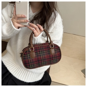 Close-up of vintage red and green plaid handbag with brown handles and gold hardware