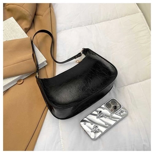 Detail of black glossy pleated faux leather shoulder bag on white quilted background