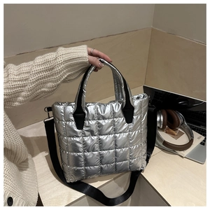 Détail du sac seau matelassé argenté avec poignées noires et bandoulière réglable