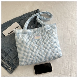 Detail of blue and white checkered quilted tote bag with heart-shaped embroidery patterns