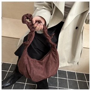 Détail du sac baguette en velours côtelé marron foncé avec poignée nouée et zip argenté