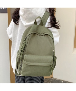 Detailaufnahme des grünen Cord-Rucksacks mit Rippstruktur und Fronttasche am Rücken