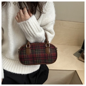 Close-up of red and green plaid handbag with leather handles and textile texture