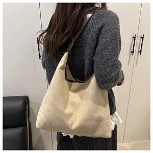 Detail of beige faux suede tote bag featuring brown leather trim and shoulder straps