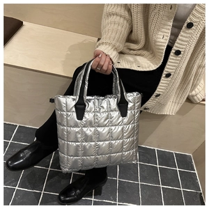 Silver quilted bucket bag with glossy padded texture and durable black woven handles