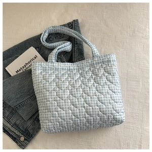 Detailed view of light blue gingham tote bag featuring heart-shaped quilted pattern texture