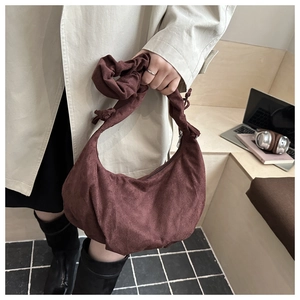 Détail du sac demi-lune en daim marron foncé avec bandoulière plissée et fermeture