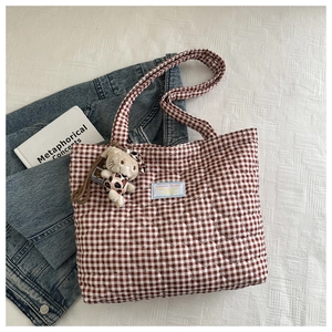 Detail of red gingham tote bag with heart-shaped quilting and plush cat charm