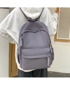Detailansicht eines grauen Cord-Rucksacks mit gewebtem Reißverschluss an einem Model