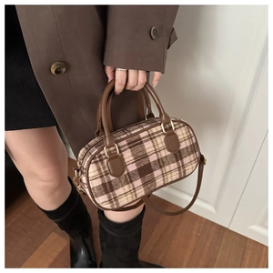 Detail of plaid wool handbag with pink brown check pattern and leather handles
