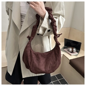 Détail du sac à main plissé marron foncé avec bandoulière scrunchie dans un décor intérieur
