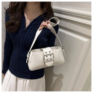 Détail du sac blanc avec une grande boucle en métal et une sangle décorative à œillets