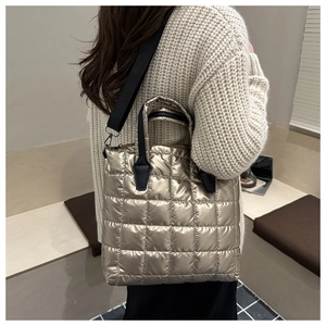 Detail of gold quilted tote bag with black strap and metallic puffer texture