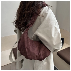 Gros plan du sac en daim marron foncé avec plis sur un trench-coat beige élégant