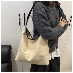 Detail of beige suede hobo bag with dark brown shoulder strap shown on a model