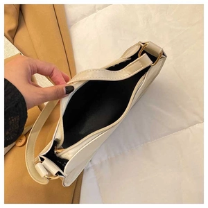 Detailed interior view of cream underarm bag showing black lining and gold hardware buckle