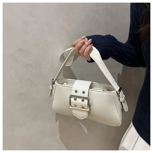 Détail d'un sac baguette en similicuir blanc crème avec grande boucle argentée et rivets