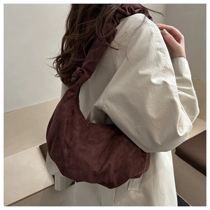 Sac croissant en daim marron foncé à bandoulière plissée porté avec un trench