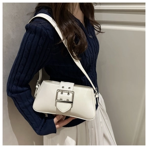 Modèle portant un sac baguette en cuir verni blanc avec une grande boucle argentée