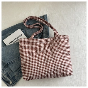Flat lay of brown and white checkered tote bag with heart quilting and flat straps